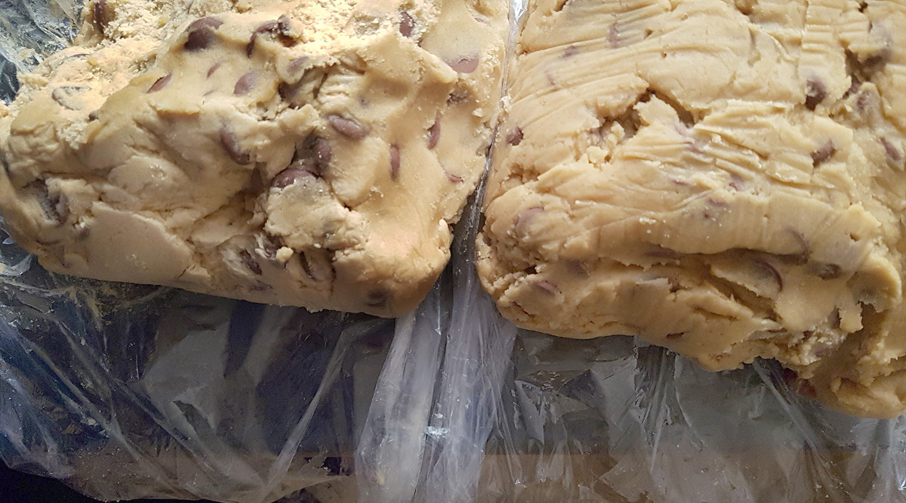 Two batches of chocolate chip cookie dough wrapped in plastic